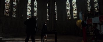 Movie still from “The Da Vinci Code” (2006), directed by Ron Howard – Two people standing in front of stained glass windows in a church; Wide shot, Low angle