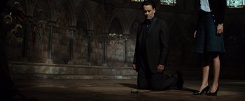 Movie still from “The Da Vinci Code” (2006), directed by Ron Howard – A man kneeling on the ground in a dark room; Wide shot, Low angle