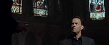 Movie still from “The Da Vinci Code” (2006), directed by Ron Howard – A man standing in front of a stained glass window; Medium shot, Low angle