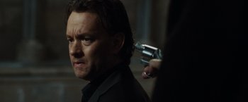 Movie still from “The Da Vinci Code” (2006), directed by Ron Howard – A man holding a gun in his hand while standing next to another man; Close Up shot, Over the shoulder angle