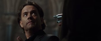 Movie still from “The Da Vinci Code” (2006), directed by Ron Howard – A man in a suit holding a gun in his hand; Close Up shot, Over the shoulder angle