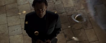 Movie still from “The Da Vinci Code” (2006), directed by Ron Howard – A man in a black suit is holding a yellow object; Close Up shot, Low angle