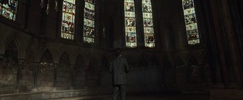Movie still from “The Da Vinci Code” (2006), directed by Ron Howard – A man standing in front of a stained glass window; Wide shot, Low angle