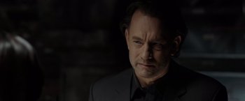 Movie still from “The Da Vinci Code” (2006), directed by Ron Howard – A man in a black suit is looking at the camera; Close Up shot, Over the shoulder angle