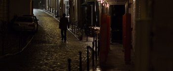 Movie still from “The Da Vinci Code” (2006), directed by Ron Howard – A person walking down a street at night; Extreme Wide shot, High angle