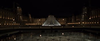 Movie still from “The Da Vinci Code” (2006), directed by Ron Howard – A man standing in front of a building at night; Extreme Wide shot, Low angle