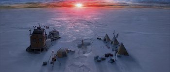 Movie still from “The Day After Tomorrow” (2004), directed by Roland Emmerich – An aerial view of an ice covered lake with tents and a person standing in the distance; Extreme Wide shot, High angle