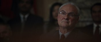 Movie still from “The Day After Tomorrow” (2004), directed by Roland Emmerich – An older man wearing glasses and a suit; Close Up shot, Over the shoulder angle