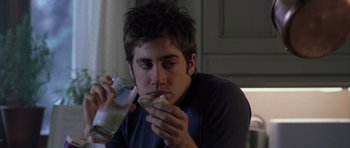 A young man is eating a sandwich and drinking milk
