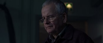 Movie still from “The Day After Tomorrow” (2004), directed by Roland Emmerich – An older man wearing glasses and a brown jacket; Close Up shot, Over the shoulder angle