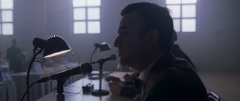 Movie still from “The Day After Tomorrow” (2004), directed by Roland Emmerich – A man sitting in front of microphones in a room; Close Up shot, Low angle