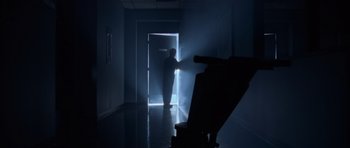 Movie still from “The Day After Tomorrow” (2004), directed by Roland Emmerich – A man standing in a dark room in front of an open door; Wide shot, Low angle