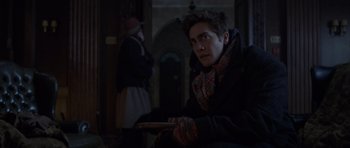 Movie still from “The Day After Tomorrow” (2004), directed by Roland Emmerich – A man in a scarf and gloves holding a book; Medium shot, Over the shoulder angle