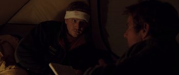 Movie still from “The Day After Tomorrow” (2004), directed by Roland Emmerich – A man with a bandage on his head is reading a book; Close Up shot, Over the shoulder angle