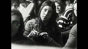 Movie still from “The Day the Music Died/American Pie” (2022), directed by Mark Moormann – Black and white photograph of a woman in a crowd of people; Close Up shot, High angle