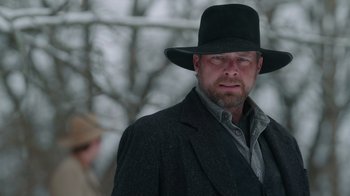A man wearing a black hat and a black coat