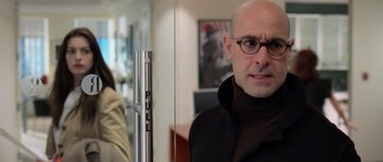 Movie still from “The Devil Wears Prada” (2006), directed by David Frankel – A bald man wearing glasses standing in front of a mirror; Close Up shot, Over the shoulder angle