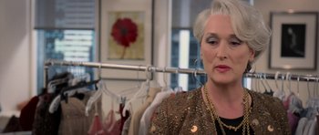 Movie still from “The Devil Wears Prada” (2006), directed by David Frankel – An older woman is looking at the camera in front of a rack of clothes; Close Up shot, Over the shoulder angle