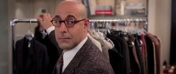 Movie still from “The Devil Wears Prada” (2006), directed by David Frankel – A bald man in a suit and tie in front of a rack of clothes; Close Up shot, Over the shoulder angle