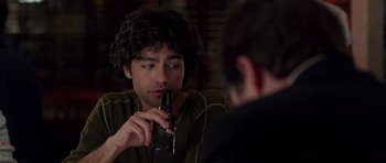 Movie still from “The Devil Wears Prada” (2006), directed by David Frankel – A man holding a beer in his hand while sitting at a table; Close Up shot, Over the shoulder angle
