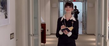 Movie still from “The Devil Wears Prada” (2006), directed by David Frankel – A woman in a black suit holding a book; Medium shot, Over the shoulder angle