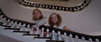 Movie still from “The Devil Wears Prada” (2006), directed by David Frankel – Two young girls standing at the bottom of a staircase; Medium shot, Low angle