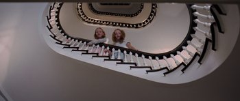 Movie still from “The Devil Wears Prada” (2006), directed by David Frankel – Two young girls standing at the bottom of a staircase; Wide shot, Low angle
