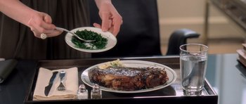 Movie still from “The Devil Wears Prada” (2006), directed by David Frankel – A plate of food on top of a table with a person holding a plate of food; Extreme Close Up shot, High angle