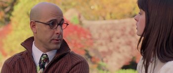 Movie still from “The Devil Wears Prada” (2006), directed by David Frankel – A bald man wearing glasses and a brown jacket; Close Up shot, Over the shoulder angle