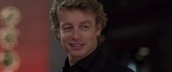 Movie still from “The Devil Wears Prada” (2006), directed by David Frankel – A person wearing a suit and smiling; Close Up shot, Over the shoulder angle