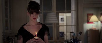 Movie still from “The Devil Wears Prada” (2006), directed by David Frankel – A woman holding a lit candle in her hands; Close Up shot, Over the shoulder angle
