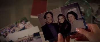Movie still from “The Devil Wears Prada” (2006), directed by David Frankel – A person holding up a picture of a family; Extreme Close Up shot, Overhead angle