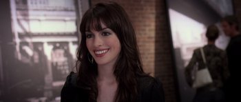 Movie still from “The Devil Wears Prada” (2006), directed by David Frankel – A woman with long brown hair smiles for the camera; Close Up shot, Over the shoulder angle