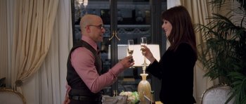 Movie still from “The Devil Wears Prada” (2006), directed by David Frankel – A man and a woman are holding wine glasses and toasting; Medium shot, Over the shoulder angle