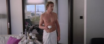 Movie still from “The Devil Wears Prada” (2006), directed by David Frankel – A shirtless man holding a coffee cup in a room; Medium shot, Over the shoulder angle