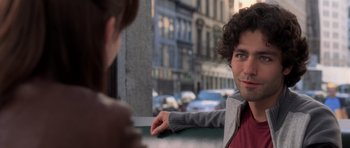 Movie still from “The Devil Wears Prada” (2006), directed by David Frankel – A man sitting next to a woman on a street; Close Up shot, Over the shoulder angle