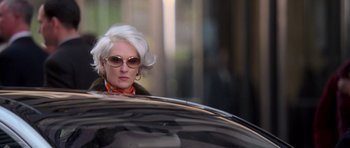 Movie still from “The Devil Wears Prada” (2006), directed by David Frankel – A woman with white hair and sunglasses looking out of a car window; Close Up shot, Over the shoulder angle