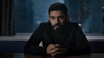 Movie still from “The Dissident” (2020), directed by Bryan Fogel – A man sitting at a table with his hands crossed; Medium shot, Low angle