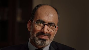 Movie still from “The Dissident” (2020), directed by Bryan Fogel – A person wearing glasses and a suit; Close Up shot, High angle