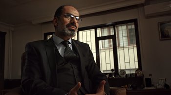 Movie still from “The Dissident” (2020), directed by Bryan Fogel – A man in a suit and tie sitting in front of a window; Close Up shot, Low angle