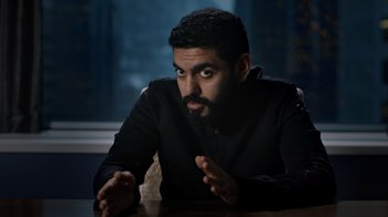Movie still from “The Dissident” (2020), directed by Bryan Fogel – A man sitting at a wooden table in front of a window; Medium shot, Over the shoulder angle