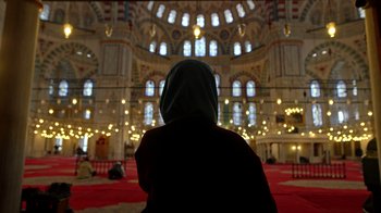 Movie still from “The Dissident” (2020), directed by Bryan Fogel – A person sitting in front of a large building; Wide shot, Low angle