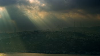 Movie still from “The Dissident” (2020), directed by Bryan Fogel – The sun is shining through the clouds over a city; Extreme Wide shot, Low angle