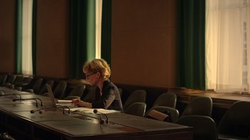Movie still from “The Dissident” (2020), directed by Bryan Fogel – A woman sitting at a table in front of papers; Wide shot, High angle