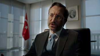 Movie still from “The Dissident” (2020), directed by Bryan Fogel – A person wearing a suit and tie; Close Up shot, Low angle