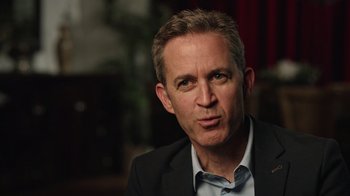 Movie still from “The Dissident” (2020), directed by Bryan Fogel – A person wearing a suit and tie; Close Up shot, Over the shoulder angle