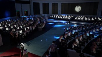 Movie still from “The Dissident” (2020), directed by Bryan Fogel – People are sitting in rows in front of a projection screen; Extreme Wide shot, High angle