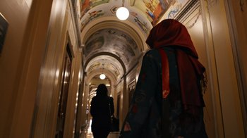 Movie still from “The Dissident” (2020), directed by Bryan Fogel – Two women walking down a hallway in a building; Medium shot, Low angle