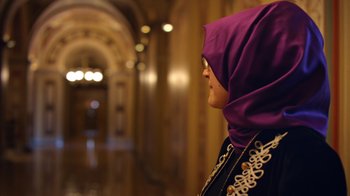 Movie still from “The Dissident” (2020), directed by Bryan Fogel – A woman wearing a purple headscarf in a hallway; Close Up shot, Over the shoulder angle