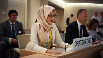 Movie still from “The Dissident” (2020), directed by Bryan Fogel – A woman with a headscarf sitting in front of a microphone; Medium shot, Low angle